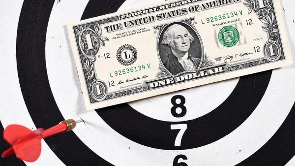 close up of red dart arrow with dollar bills on dartboard for background