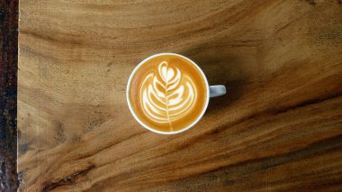 Ahşap arka planda bir fincan latte sanat kahvesi.                                                                                                                                                                                           