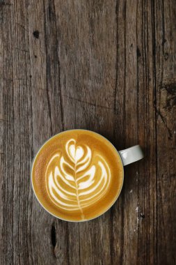Ahşap arka planda bir fincan latte sanat kahvesi.                                                                                                                                                            
