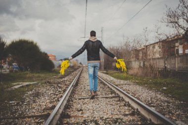 Elinde sarı mimoza çiçekleri olan genç bir adam baharda dışarı çıkıyor..