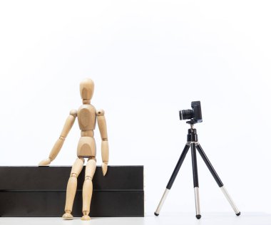 Tahta adam heykelciği ve üç ayaklı kamera.