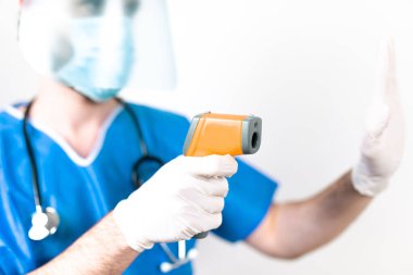 Beyaz arka planda duran lazer termometresi olan doktor.