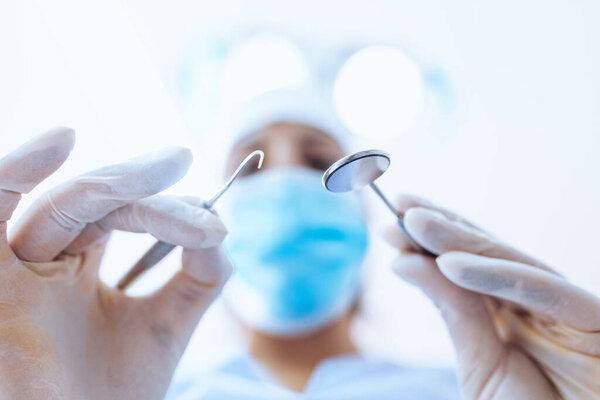 Dentist with tools above patient
