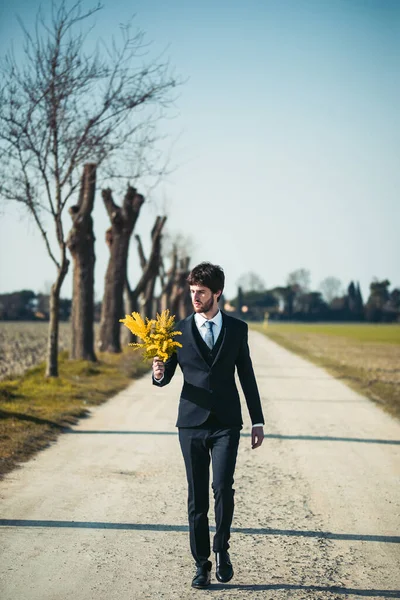 Portrait Man Suit Posing Holding Yellow Mimosa Flowers Blurred Natural — Stok Foto