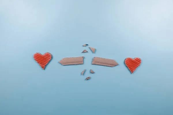 Breaking love concept with red carton hearts on blue background