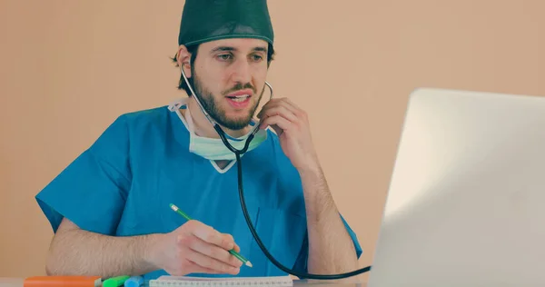 Mężczyzna Lekarz Stetoskopem Siedzi Przy Stole Laptopem — Zdjęcie stockowe