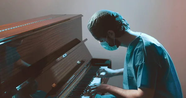 doctor in uniform and in the mask playing piano