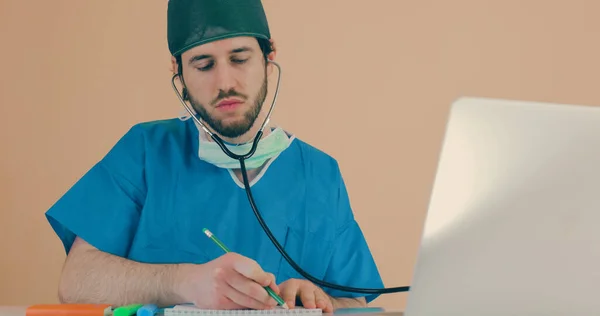 Mężczyzna Lekarz Stetoskopem Siedzi Przy Stole Laptopem — Zdjęcie stockowe
