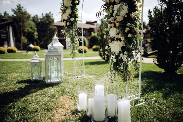 Arco de boda de flores frescas blancas decoradas con velas y candelabros en el jardín de verano al aire libre — Foto de Stock