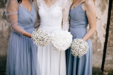 Gelin ve arkadaşları ellerinde güzel beyaz çiçek buketleri tutuyorlar.