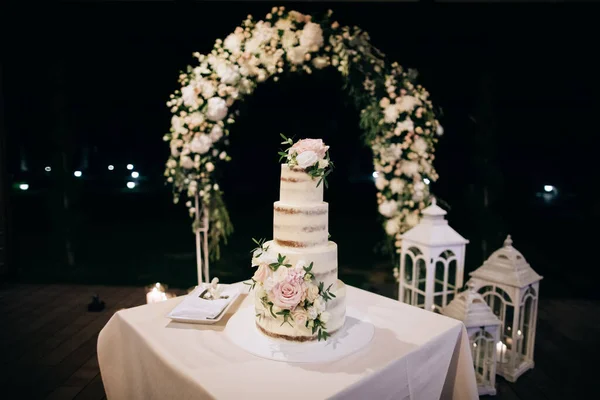 Beautiful wedding cake with candles and flowers outdoors — Stock Photo, Image