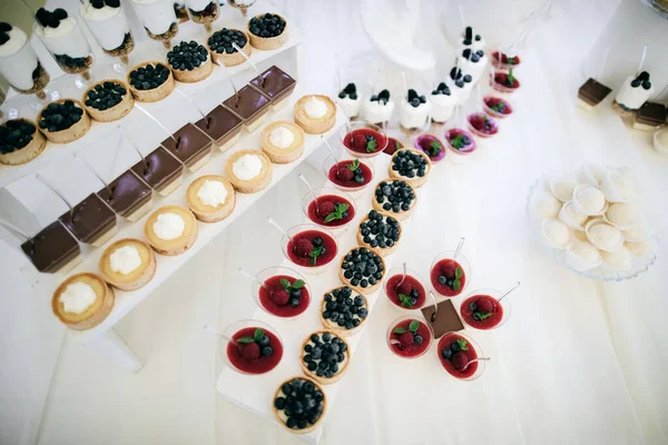 Dulces y pasteles con bayas frescas frambuesas, moras, hojas de menta en la recepción de la boda —  Fotos de Stock