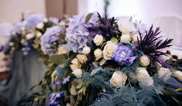 Bruiloft decor van verse blauwe en witte bloemen op tafels op een bruiloft in een restaurant — Stockfoto