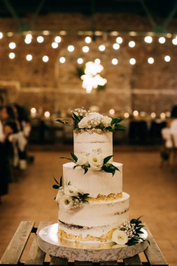 Beyaz düğün pastası bir restorandaki düğün töreninde masanın üstünde.