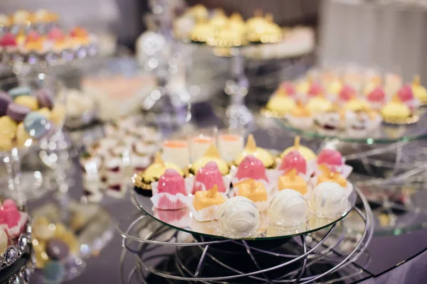 ミラーテーブルの上に黄色とピンクのケーキとエレガントなキャンディーバー — ストック写真
