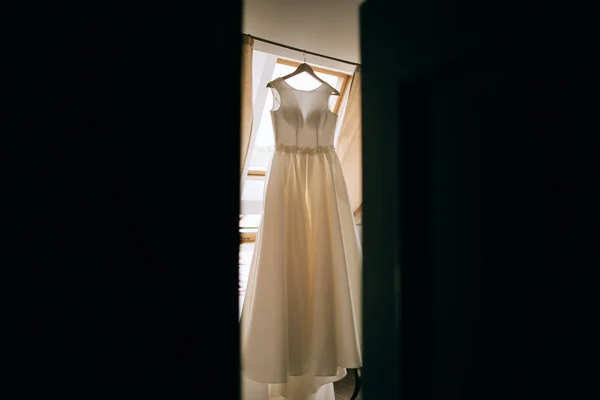 Gaun pengantin yang indah tergantung di jendela. Pagi pengantin wanita — Stok Foto