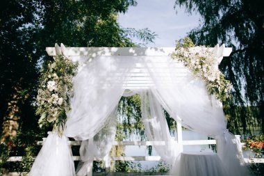 Beautiful arch with fresh flowers for the wedding ceremony in the summer garden