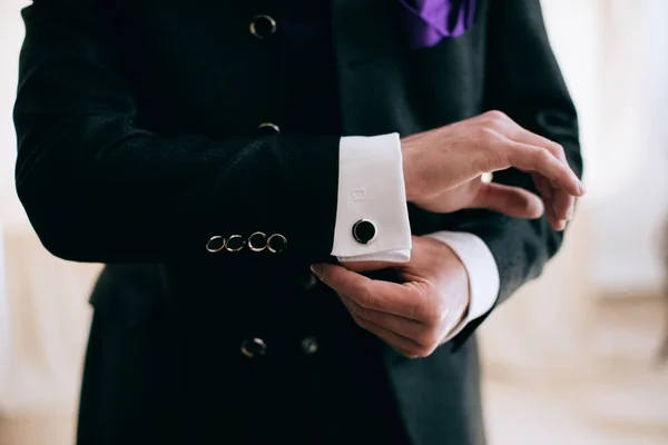 Un hombre con traje de negocios se sujeta un botón en la manga. Concepto empresarial . — Foto de Stock