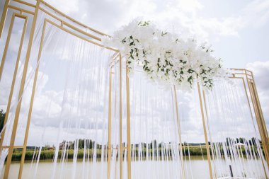 Beautiful white arch  for the wedding ceremony  on the lake