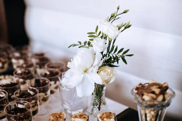 Kue manis dengan buah beri dan krim di meja makan di pesta pernikahan dengan hiasan bunga putih — Stok Foto