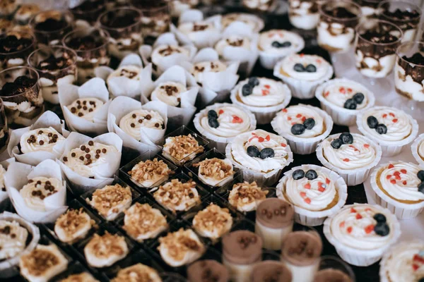 Sladké chutné dorty s bobulemi a smetanou na dezertním stole na svatební hostině — Stock fotografie