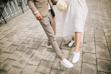 Gelin ve damat sokakta ayakkabılarını gösteriyor. Klasik düğün ayakkabıları değil.