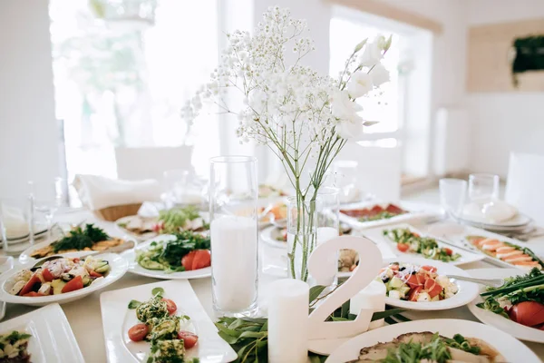 Прикраса весільного столу в білому, їжа на столах і букети квітів — стокове фото