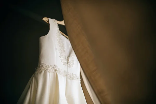 婚纱装饰 漂亮的白色衣服挂在窗边的衣架上 新娘早晨 — 图库照片