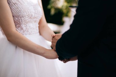 Gelin ve damat düğün töreninde el ele tutuşuyorlar. Aşk konsepti. Aşkın Sözü
