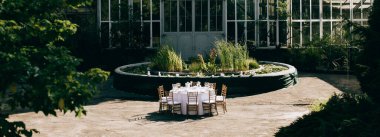 Parktaki açık havada romantik bir akşam yemeği. Parkta gözlüklü ve çiçek buketli bir masa. Açık hava yemek servisi..