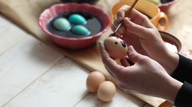 Bir kadın püsküllü Paskalya yumurtası çiziyor.