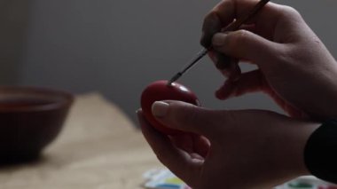 Paskalya için hazırlanıyorum. Kız tavuk yumurtalarını geleneksel desenli kırmızı boyayla boyuyor.