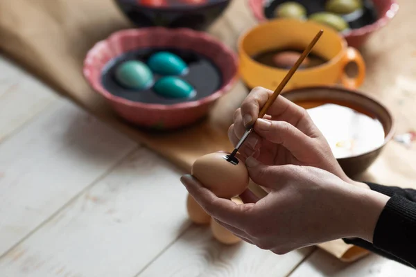 A woman with a tassel paints an Easter egg. Preparing for Easter