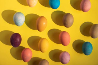 Sarı arkaplanda renkli Paskalya yumurtaları.