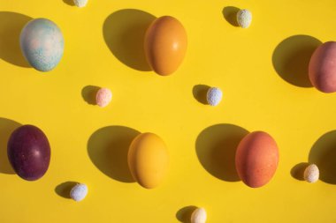 Sarı arkaplanda renkli Paskalya yumurtaları.