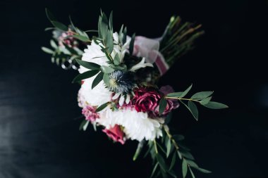 Koyu arkaplanda beyaz kasımpatı buketi ve mor güller.