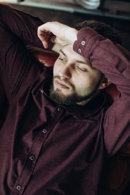 Genç sakallı adam evde dinleniyor.