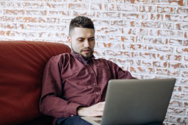 Genç adam evde bilgisayarın başında uzaktan çalışıyor..