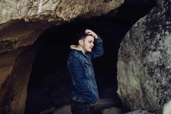 Sad man stands in a dark cave. The concept of loneliness