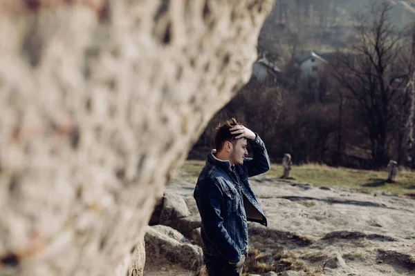 一个年轻人站在一块大石头旁边 — 图库照片