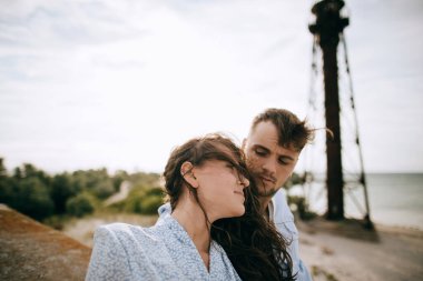 Deniz kıyısındaki bir evin çatısında birbirine sarılan genç çift.