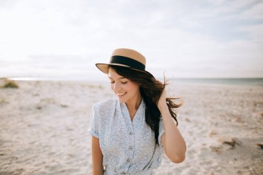 Kumsalda gülümseyen şapkalı genç bir kadın. yaz tatili