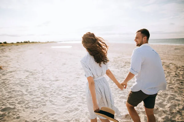 Happy young couple walking on summer beach