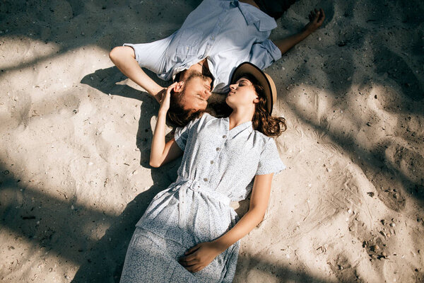 Young couple lying on the sand at the beach and kissing. Love at sea