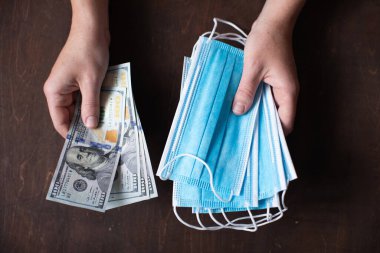 Elinde dolar tutan kadın para ve tıbbi koruyucu maskeler tutuyor. Karantina sırasında sosyal ve ekonomik sorunlar