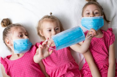 Koruyucu tıbbi maskeli pembe elbiseli küçük çocuklar. Küresel karantina. Koronavirüs salgını
