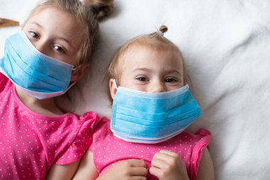 Koruyucu maske takmış iki küçük kız çocuğu. Koronavirüs salgını sırasında küresel karantina kavramı