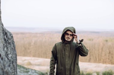 Açık havada, güneş gözlüklü bıyıklı ve sakallı şık bir adamın portresi.