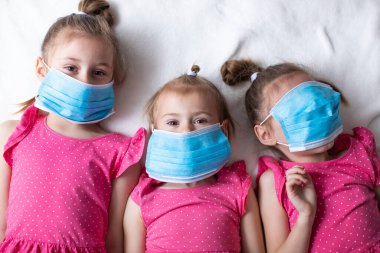 Koruyucu tıbbi maskeli üç küçük kız. Virüslere ve koronavirüse karşı koruma