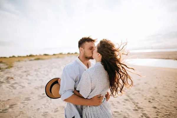 黎明时分 一对年轻夫妇在荒芜的海滩上接吻 — 图库照片